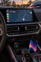 Adaptador CarPlay inalámbrico enchufado en un BMW M4 con el mapa en pantalla y el móvil sin cable