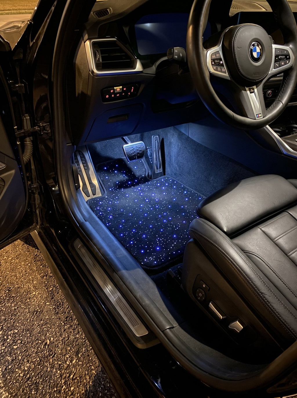 Alfombrillas de cielo estrellado encendidas en azul en un BMW de noche