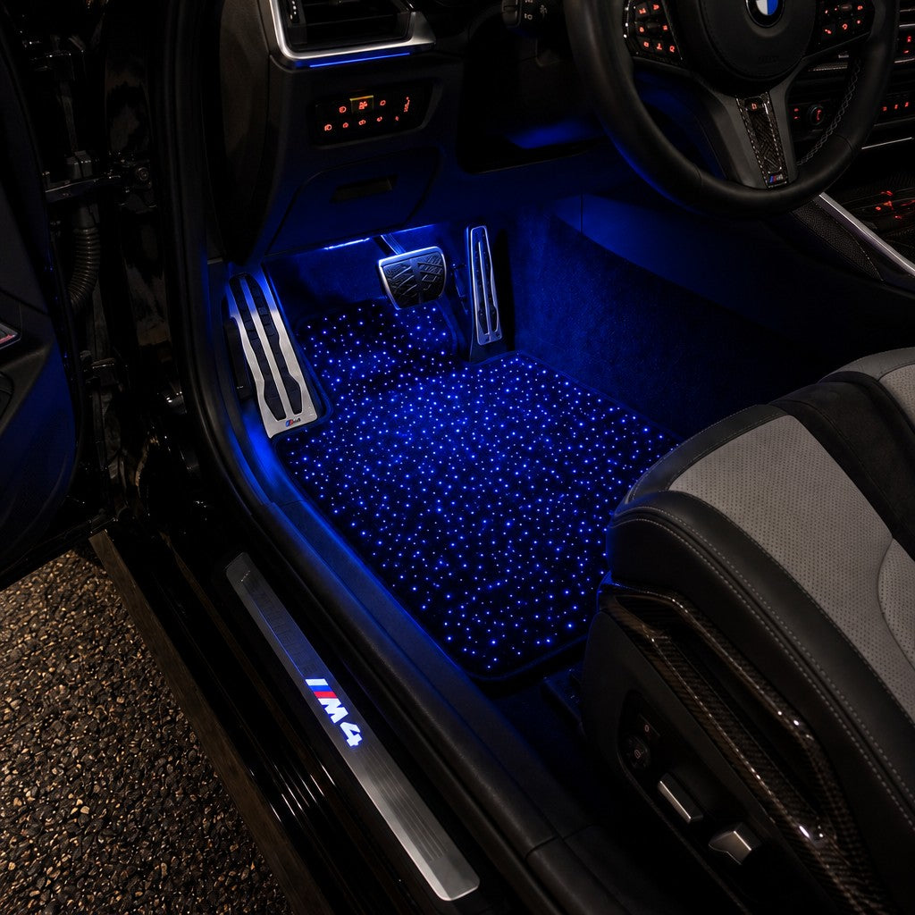 Alfombrilla de cielo estrellado encendida en azul en el puesto del conductor de un BMW M4 de noche