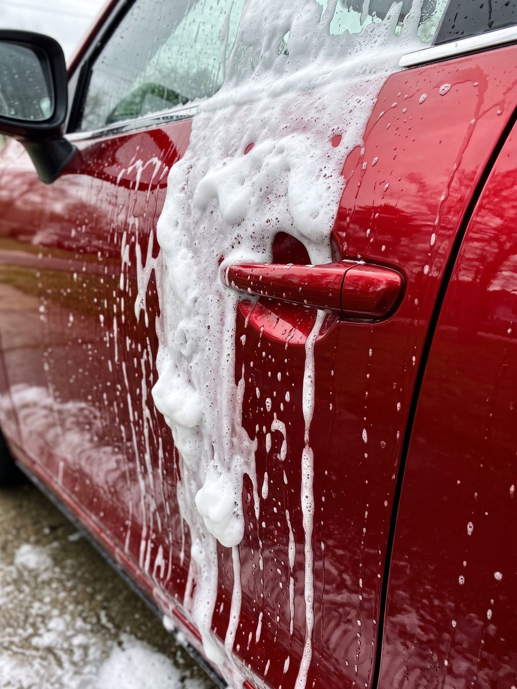 Espuma densa cayendo por la puerta de un coche rojo