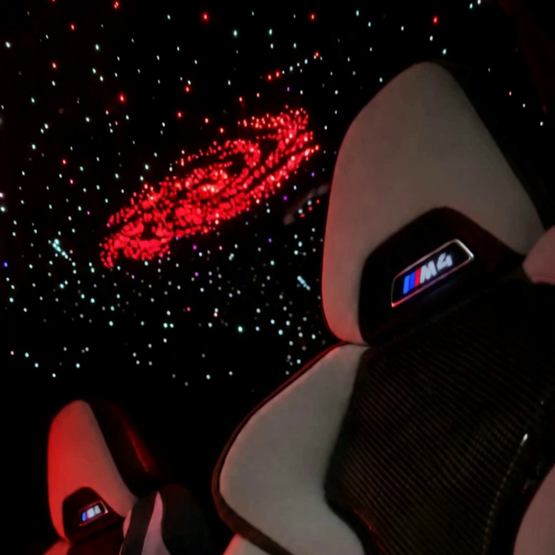 Cielo estrellado de fibra óptica en rojo con galaxia en el techo de un BMW M4 de noche