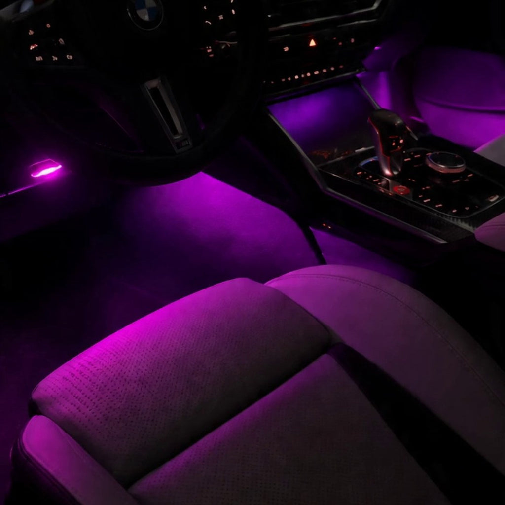 Luces de pies inalámbricas encendidas en magenta en un BMW M4 de noche
